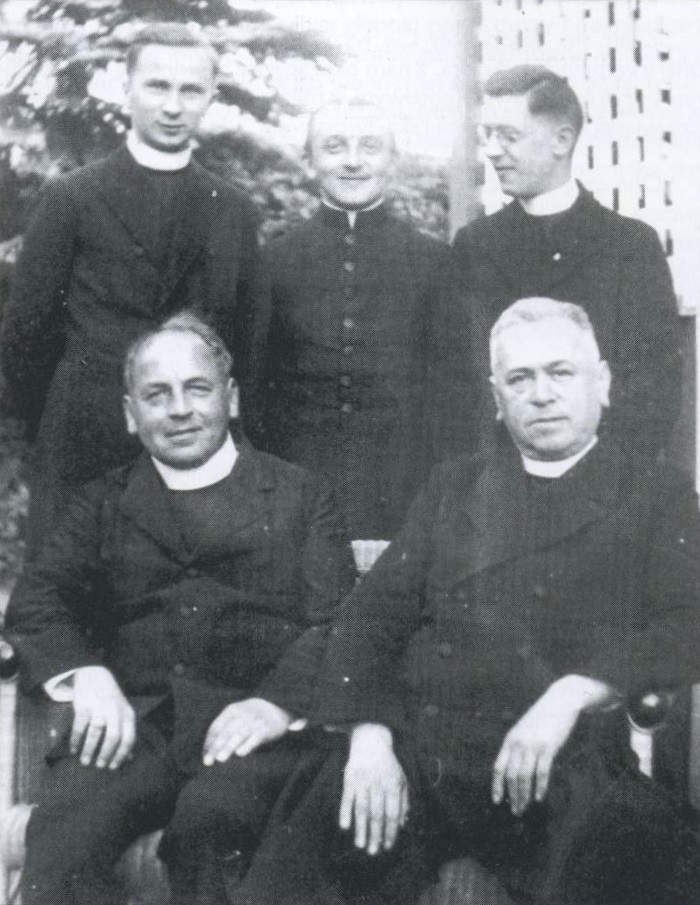 14. Ks. G. Hirschfelder w otoczeniu księży (pierwszy z lewej u dołu: ks. Augustin Hauffen – prob. p-fii św. Bartłomieja w Kudowie-Z, Czermnej).